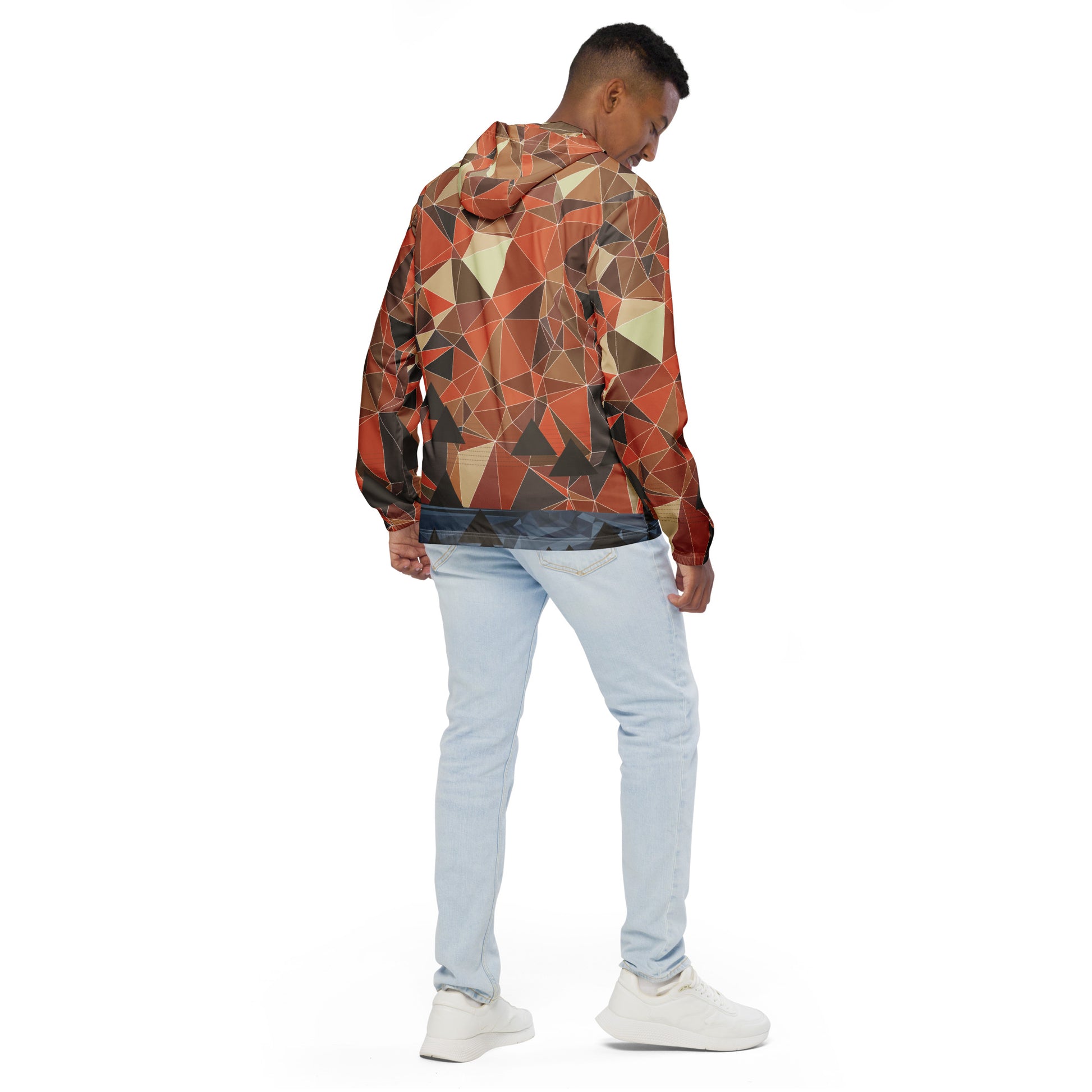 Person wearing a multicolor geometric patterned windbreaker jacket and light blue jeans on a white background