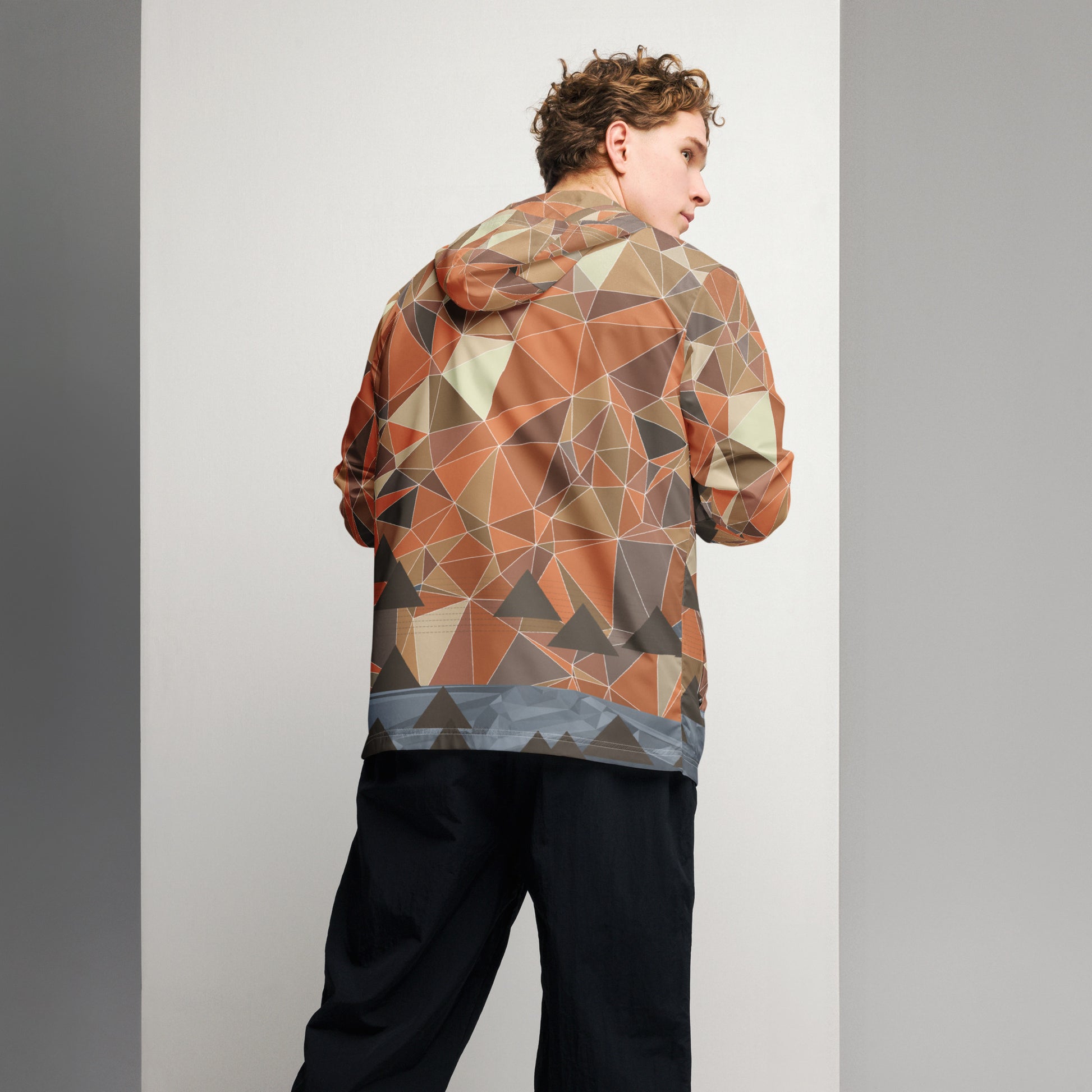 Person wearing a multicolor geometric patterned windbreaker jacket against a plain background