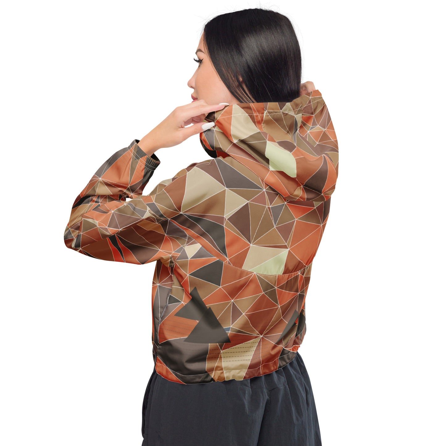 Woman wearing a cropped multicolor geometric patterned windbreaker jacket on a white background