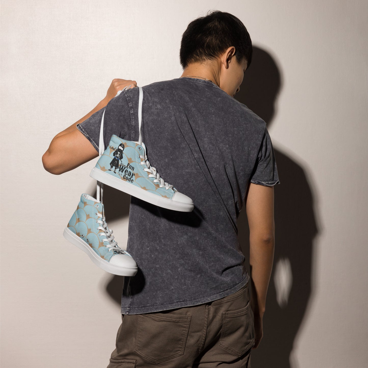 Person holding a pair of light blue high-top sneakers with a ninja graphic and 'Fun Wear Code' text logo, and white soles against a plain background